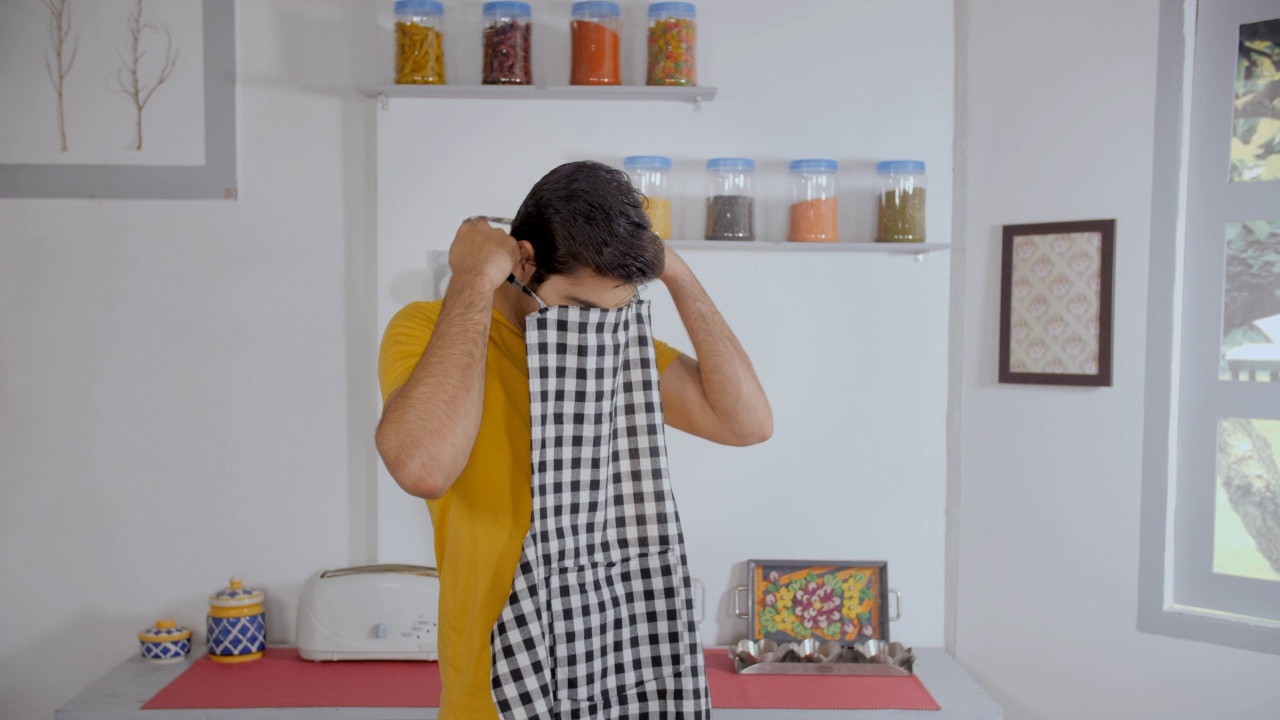 现代印度男人在厨房里准备做饭和系围裙视频素材