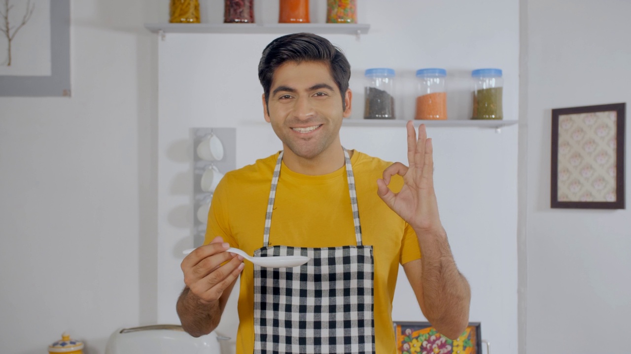 微笑着的年轻印度厨师在厨房里准备和检查他的饭菜视频素材