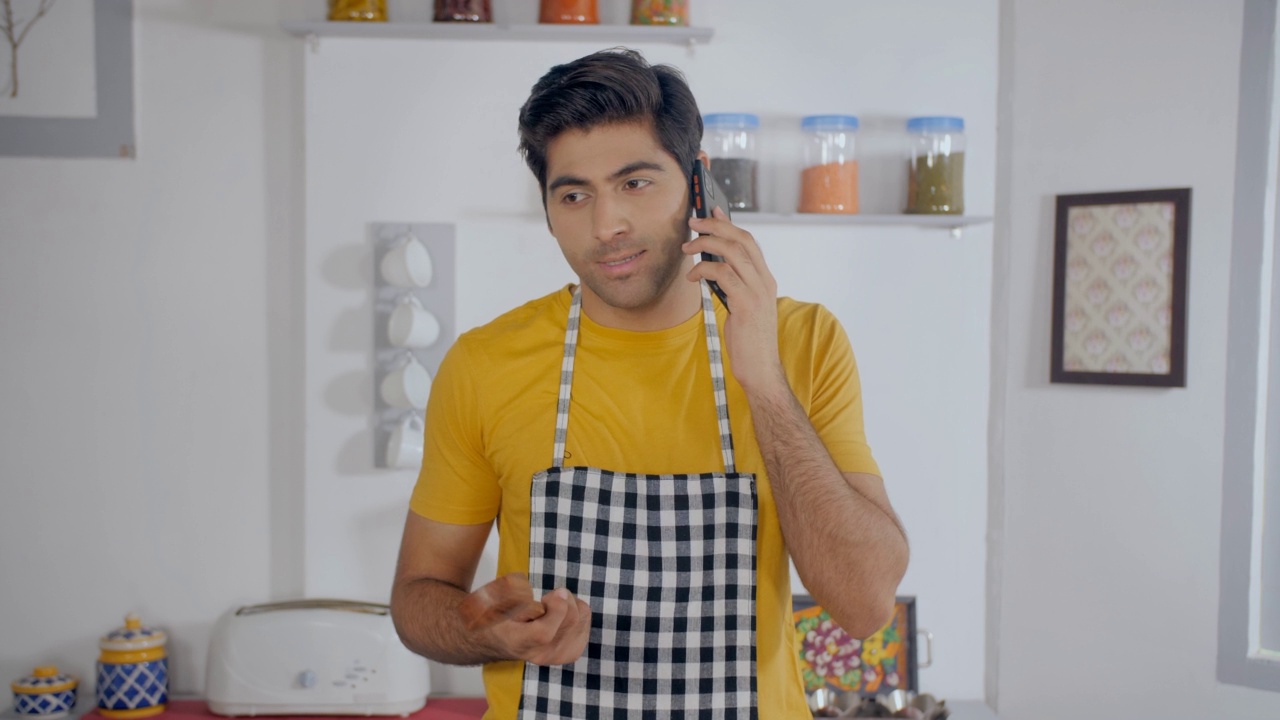 微笑的印度小男孩在厨房里，穿着便装，正在打电话视频素材