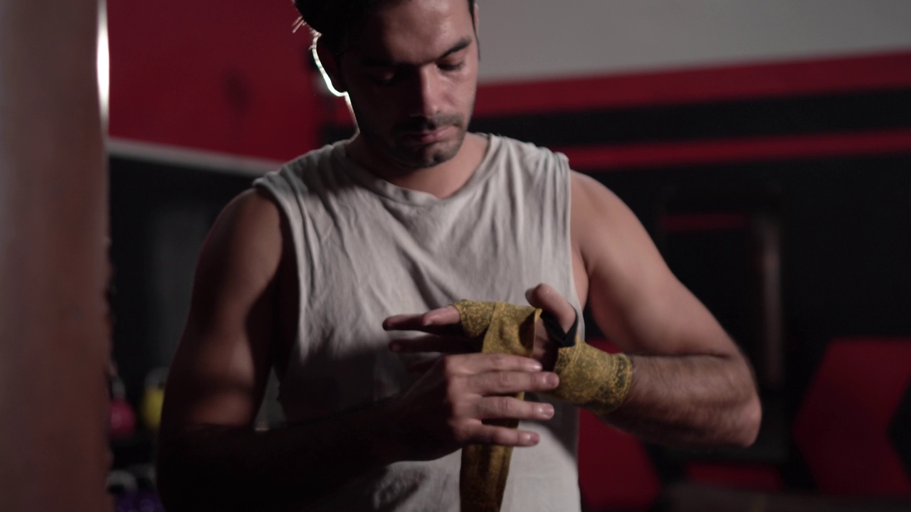 一名男子正在用拳击绷带包扎双手，以进行训练和积极的运动。强壮的拳击运动员包扎双手以保护关节，泰拳运动员视频下载