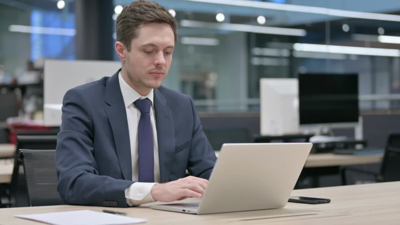 商人在办公室使用笔记本电脑时背痛视频素材