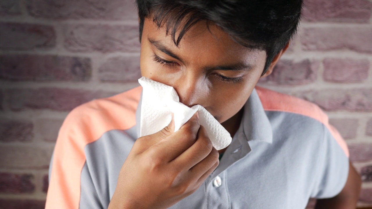 得了流感的少年用餐巾擤鼻涕。视频下载