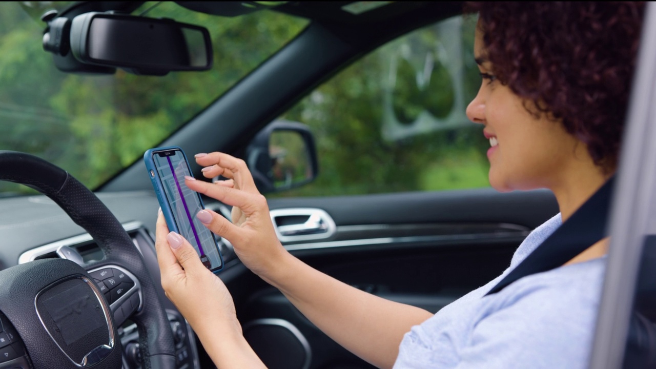 开朗漂亮的女人在开车前在手机上设置GPS视频素材