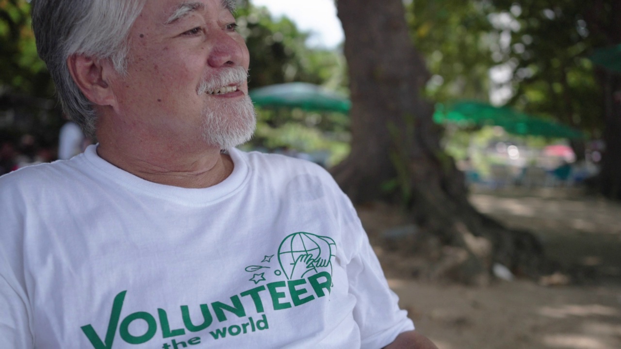 老人穿志愿者衬衫儿童和家庭活动志愿者为泰国海滩清洁。视频素材