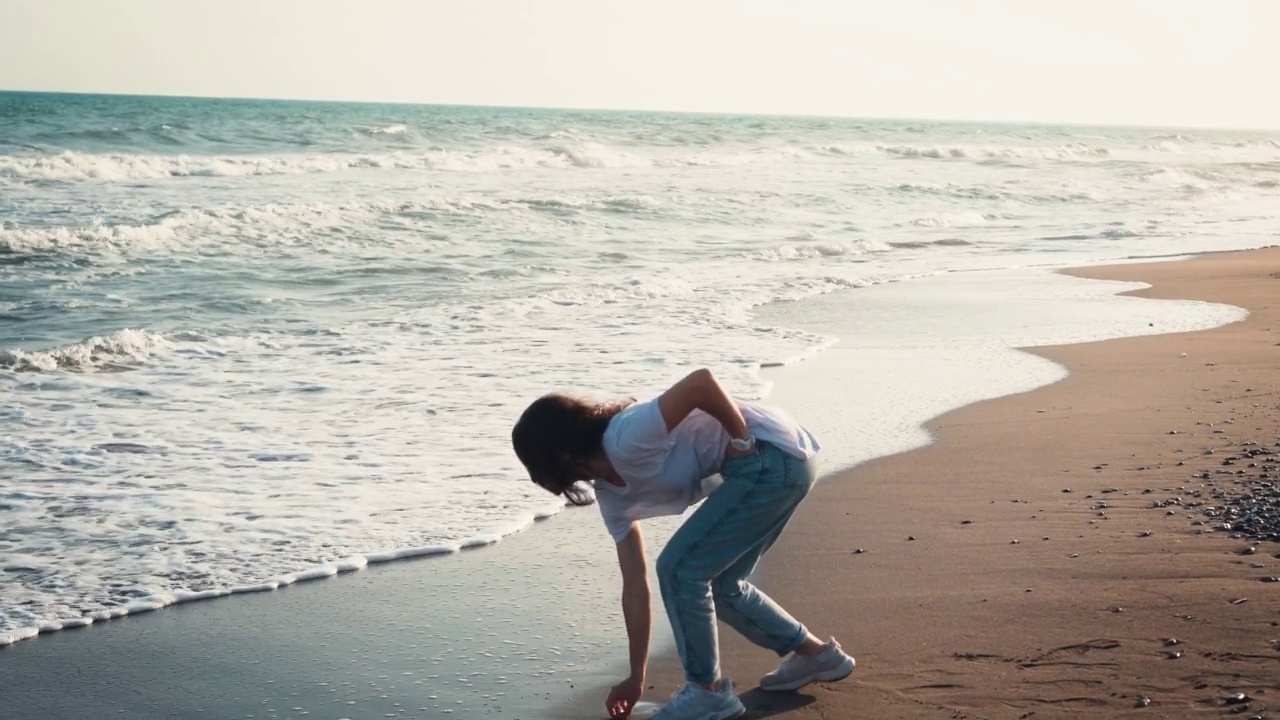 一个年轻女子向海浪中扔石头视频下载