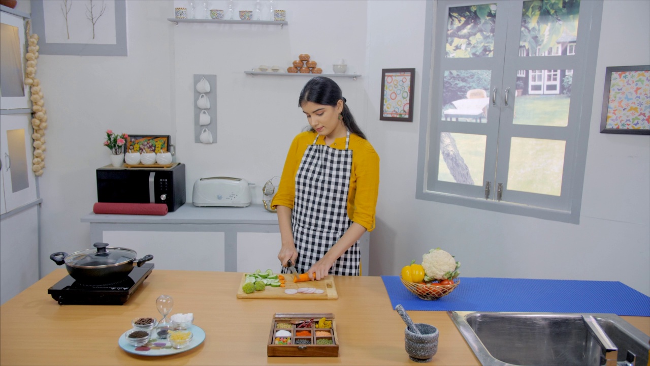 一个美丽的女孩在她的厨房里切新鲜的蔬菜准备健康的食物视频素材