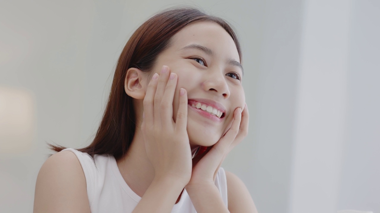 特写头像微笑的亚洲女孩与自然的妆容和健康光滑的皮肤。视频下载