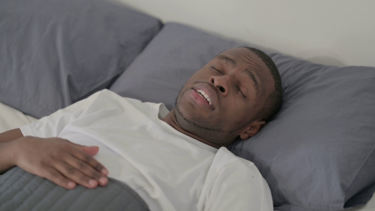 非洲男子在床上醒着咳嗽，特写视频素材