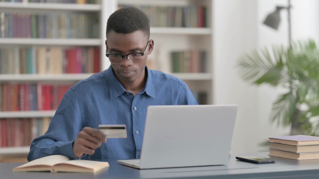 兴奋的非洲年轻人用笔记本电脑在网上购物视频素材