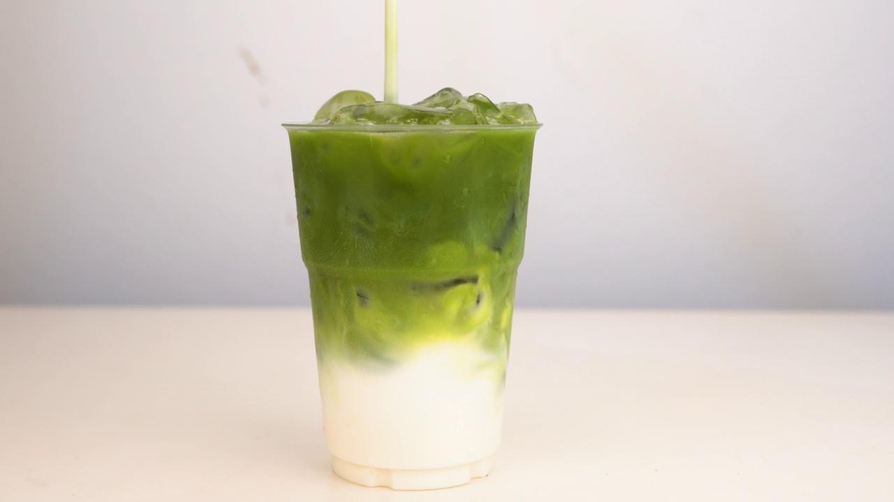 冰拿铁抹茶绿茶在塑料玻璃孤立的白色背景。视频4 k视频素材