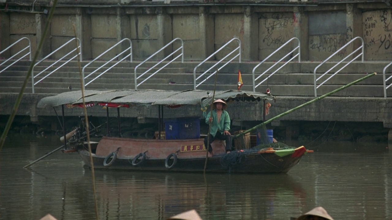 西贡附近港区角度中等。楼梯在岸上。船，人用篙或桨在水里。小艇。可能是钓鱼，渔民视频素材
