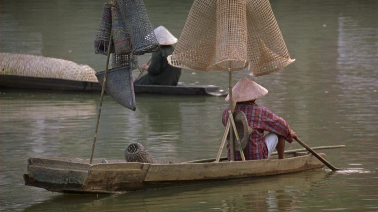 西贡附近港区角度中等。船，孩子们在泻湖或河里游泳。在小吃摊准备饭菜的女人。可能是海滩食品小贩视频下载