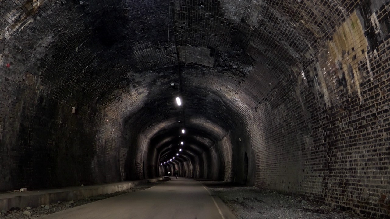 在山顶区的Cressbrook隧道内骑自行车的曲线女子视频下载