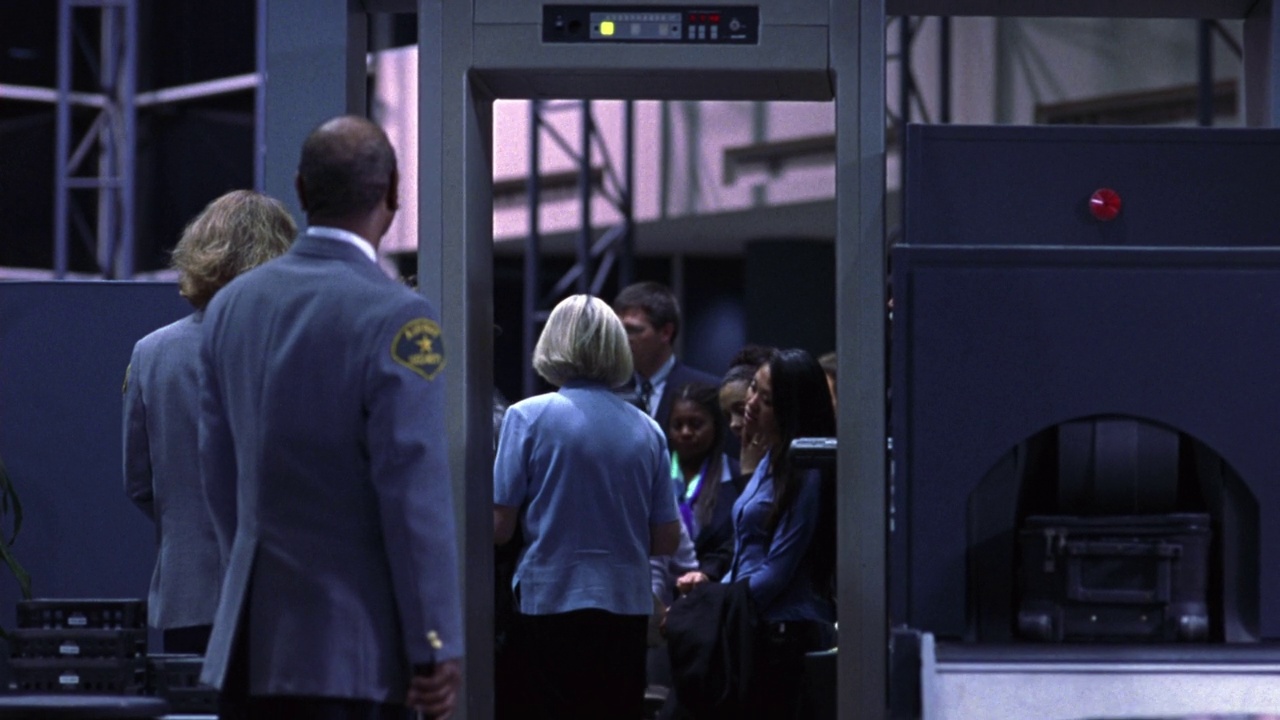机场候机楼或登机口安检门角度适中。左边看到保安，右边看到行李通过x光扫描设备。旅客通过安检门，带上行李向左走视频素材