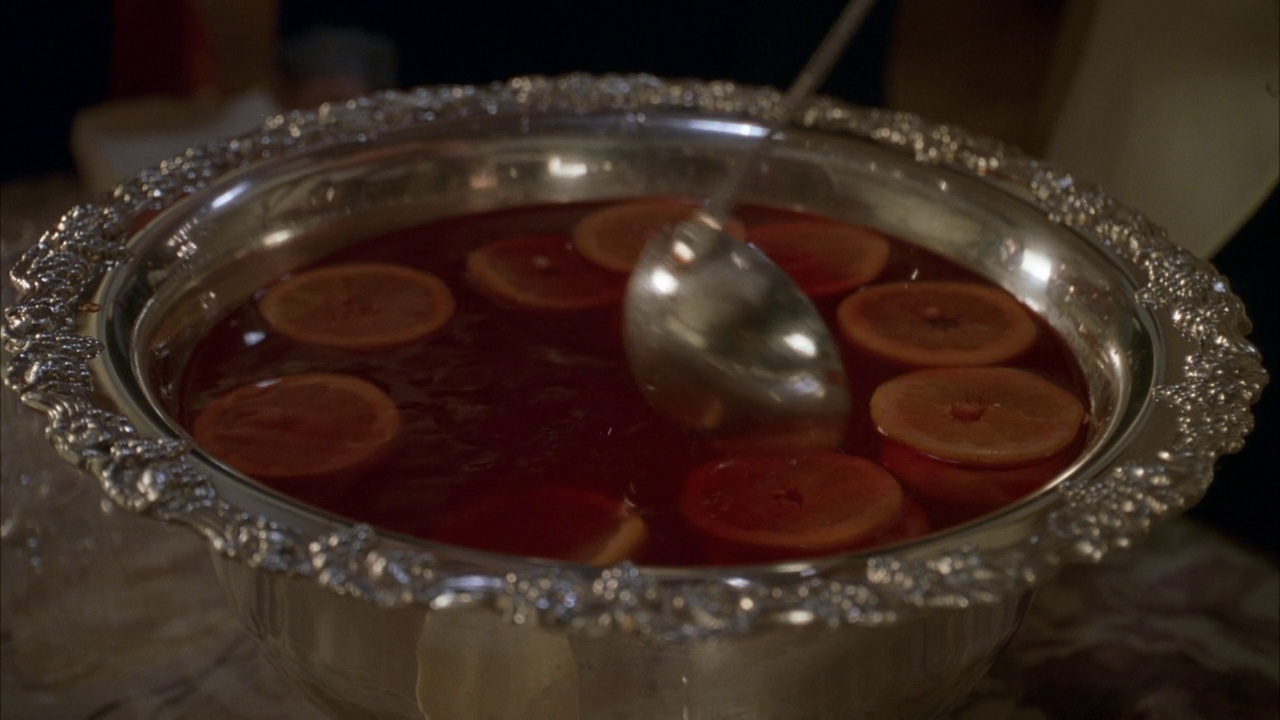 银色潘趣酒碗里红色饮料的闭合角度。看勺子搅拌饮料和柠檬片。可能是在舞会、宴会或其他特殊场合视频素材