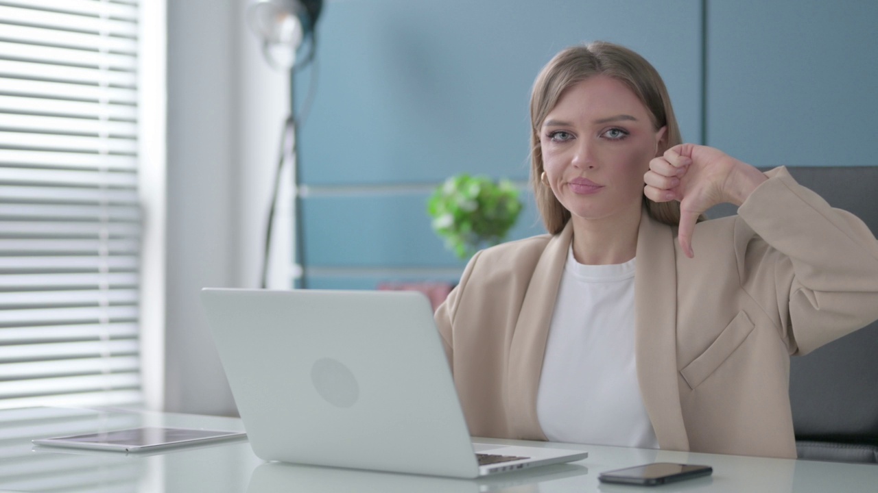 女商人在办公室使用笔记本电脑时表现出大拇指向下的手势视频素材