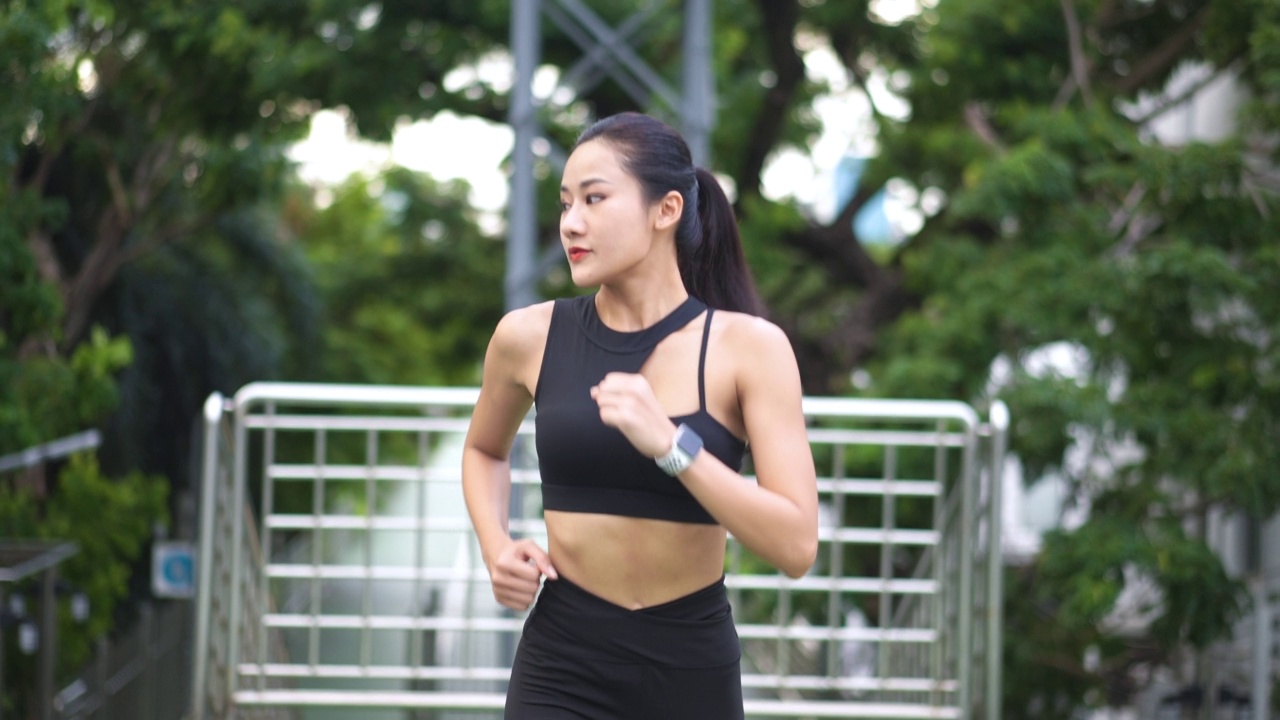 年轻女运动员在城市里跑步的慢动作剪辑视频素材