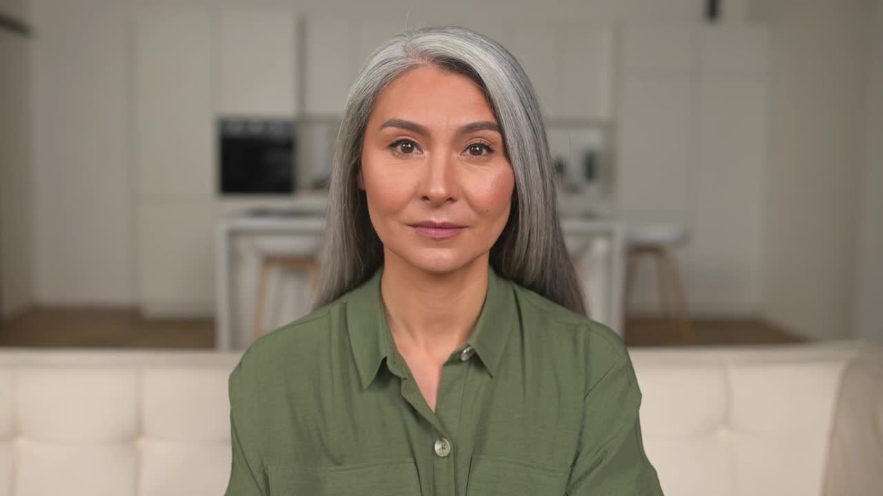 迷人的灰白头发的50多岁亚洲女人的头像看着相机视频素材