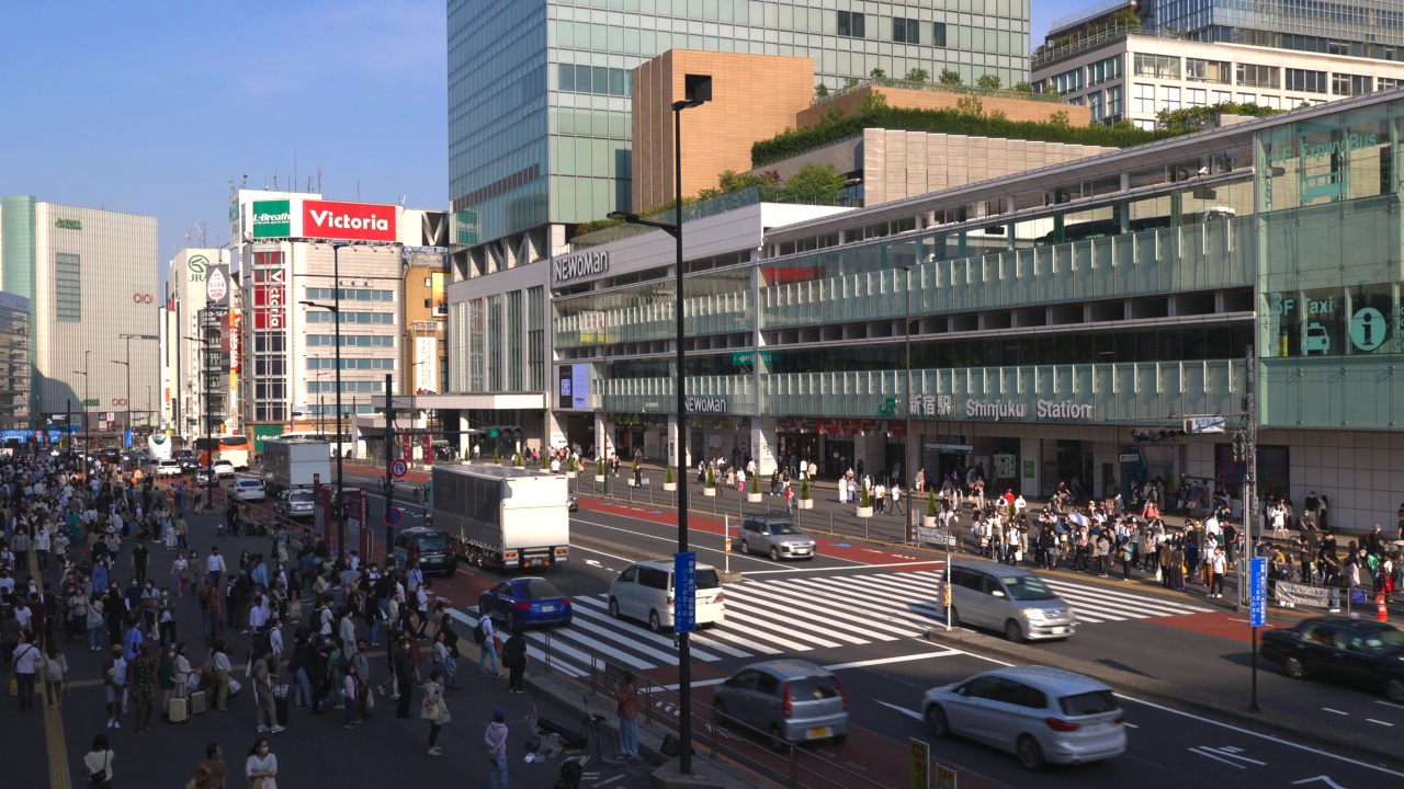 在日本东京新宿车站南出口，车辆穿梭在高楼林立的海道街视频素材