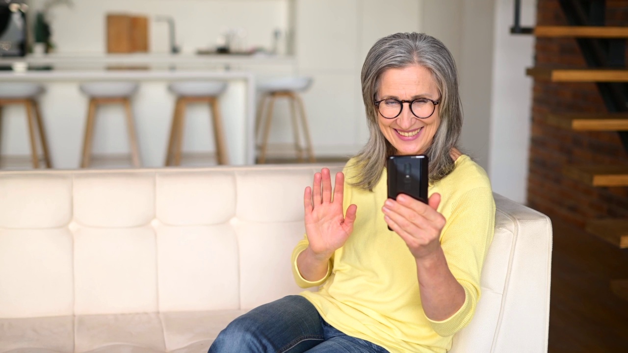 高兴成熟的灰色头发的女人女士通过视频连接在手机上在线交谈视频素材
