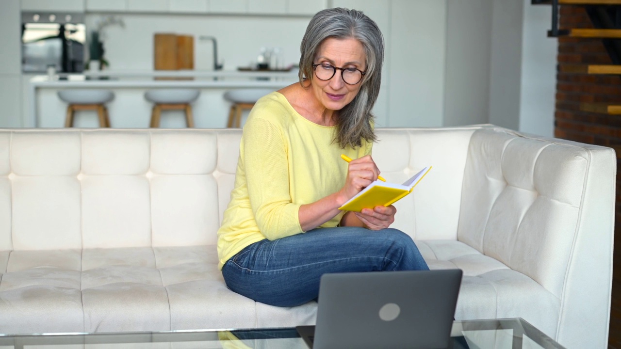 一位精力集中的退休妇女正在使用笔记本电脑在线学习视频素材