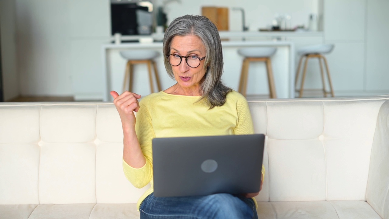 开朗自信的高级女性使用笔记本电脑进行视频连接，远程会议视频素材