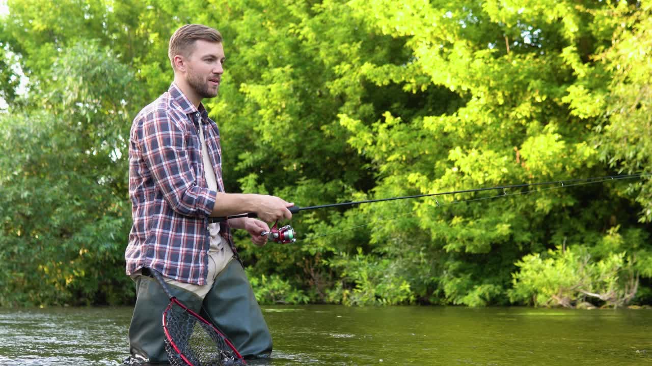 一个渔夫把一根鱼竿扔进了齐膝深的河水里。飞钓鳟鱼。暑假和人们的观念视频素材