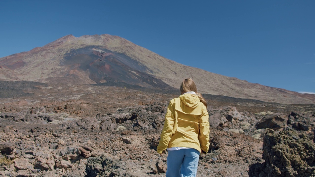 泰德，特内里费岛，加那利群岛，西班牙。在泰德火山的一个巨大火山口，年轻的女子沿着熔岩岩石中的火山沙徒步旅行视频素材