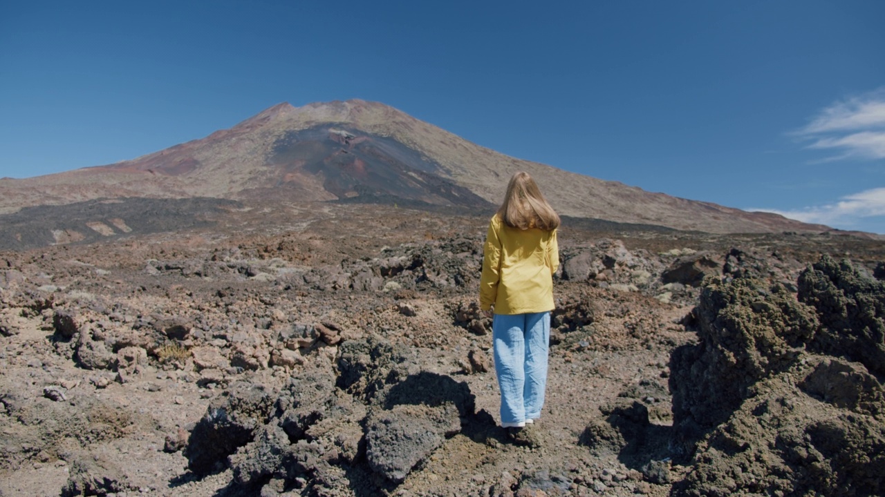 泰德，特内里费岛，加那利群岛，西班牙。在泰德火山的一个巨大火山口，年轻的女子沿着熔岩岩石中的火山沙徒步旅行视频素材