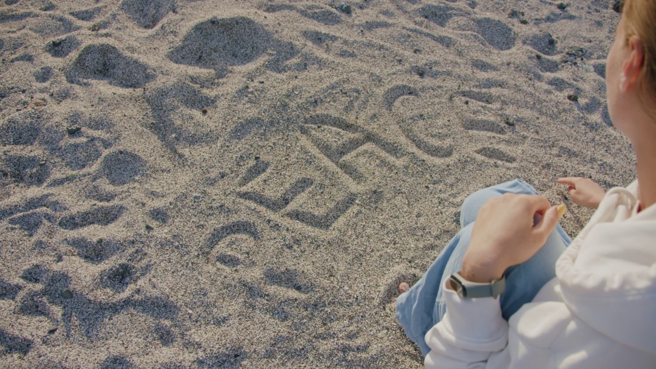 年轻女子在热带海滩的白沙上写和平字。特内里费视频素材