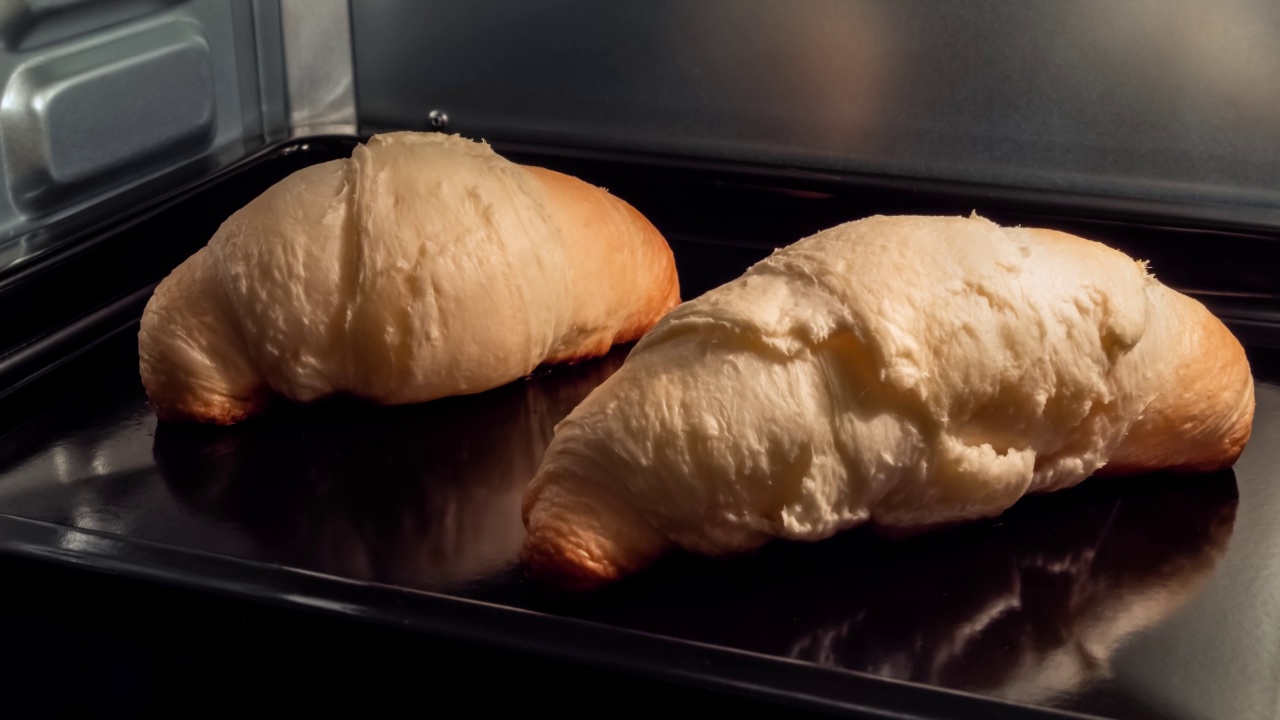 时间流逝——两个自制的牛角面包在家里的电烤箱中烘烤和升起视频素材