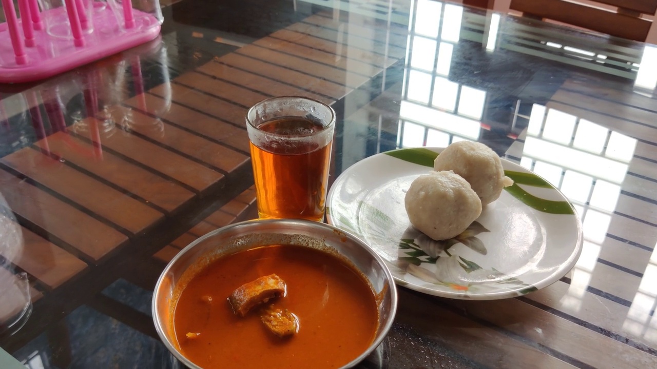 一杯红茶(苏莱玛尼)和美味的喀拉拉邦风格的早餐，白色的小吃(Kozhukatta)和鱼咖喱放在桌子上视频下载