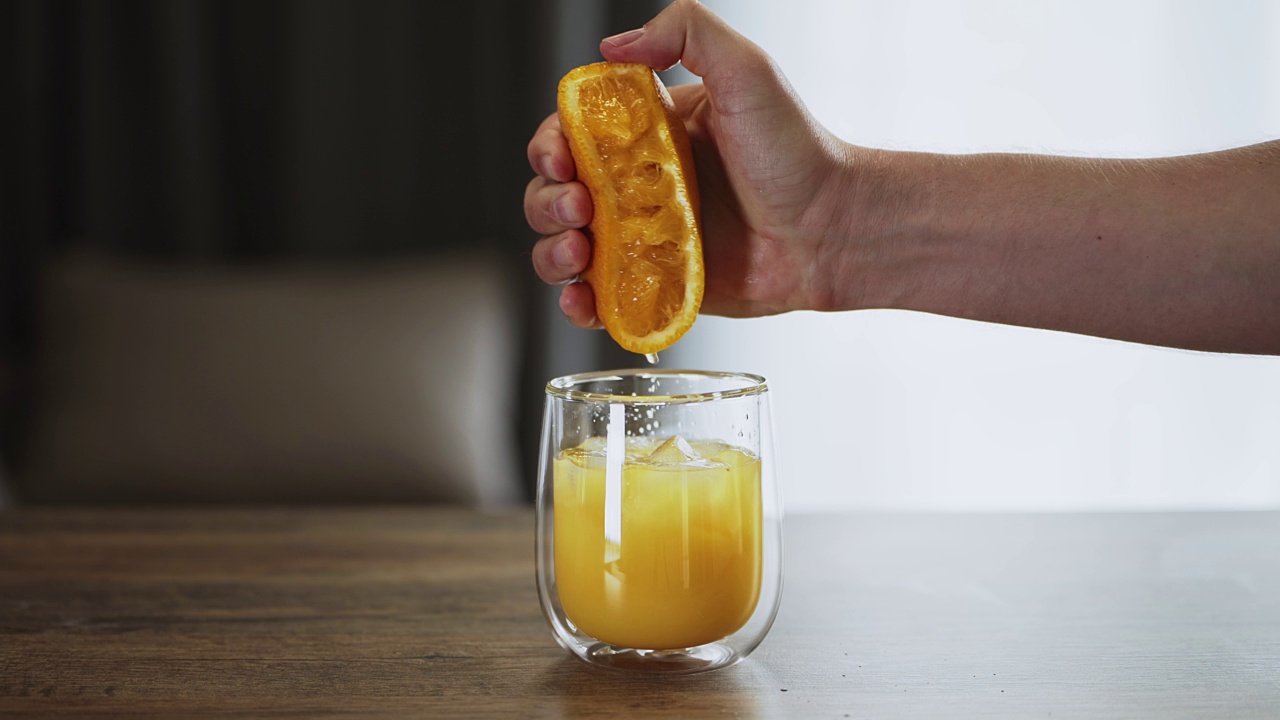 男人把橙汁挤进杯子里。简单的营养早餐视频下载