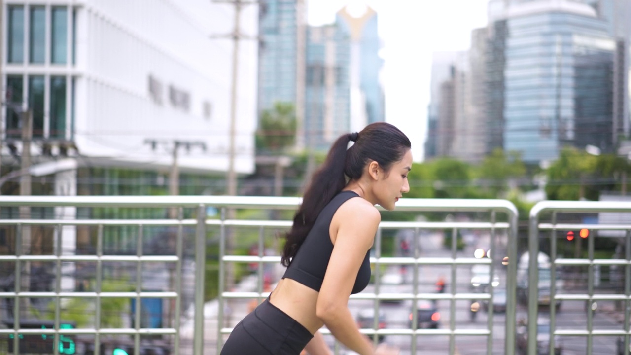年轻女运动员在城市里跑步的慢动作剪辑视频素材