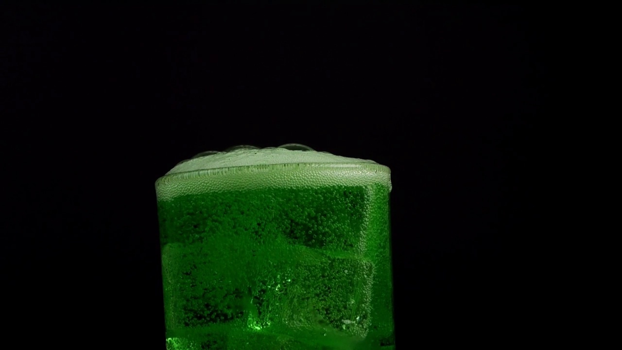慢动作的绿色水倒入玻璃特写的黑色背景视频下载