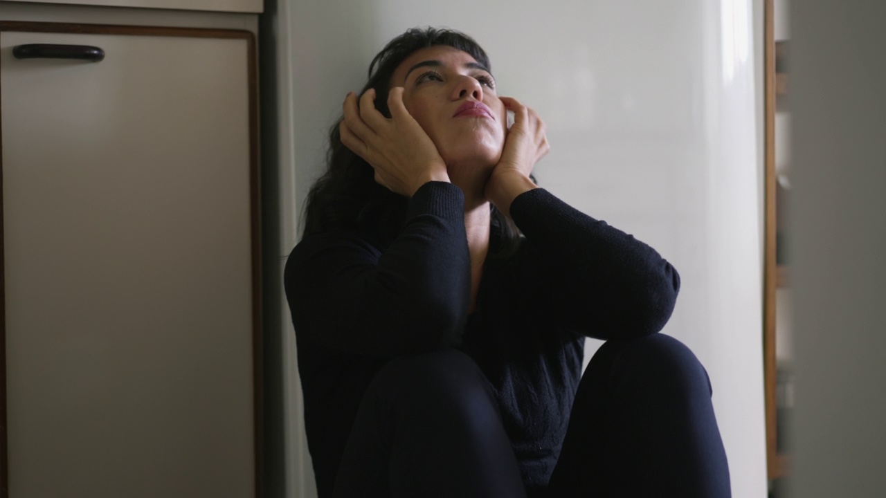 一个焦虑的西班牙裔拉丁裔妇女坐在地板上，被各种问题压得喘不过气来视频素材