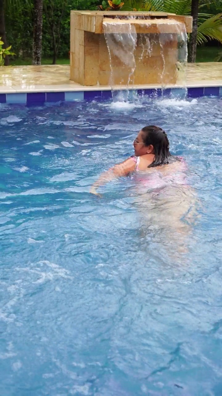 拉丁成熟女人在户外游泳池旁放松视频下载