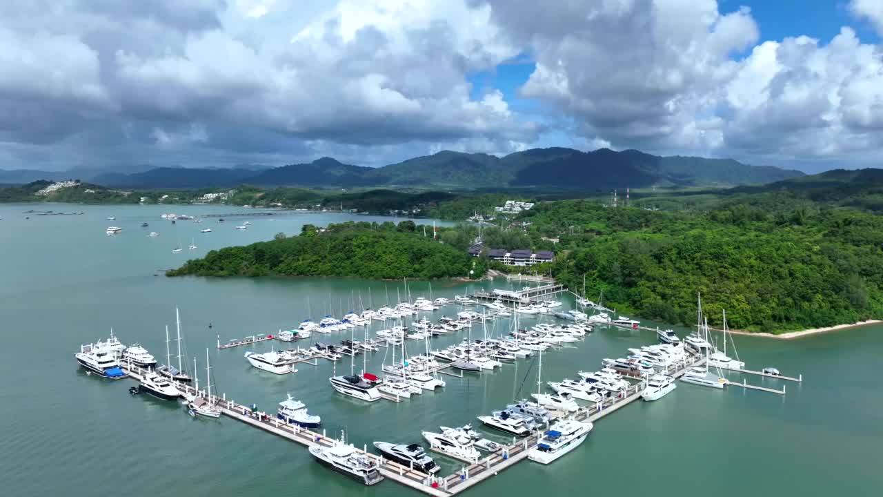在晴朗多云的蓝天下，白色游艇停泊在泰国普吉岛鳌宝大滨海湾。视频下载