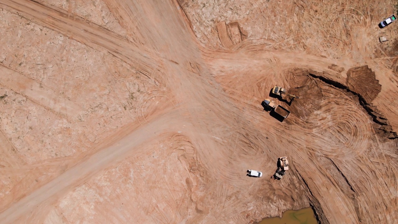 挖掘机将沙子装进大卡车，鸟瞰图视频素材