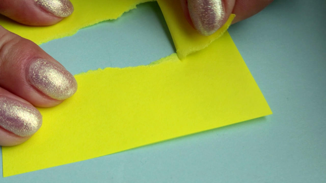 4k视频中，一名女子用手撕毁了一面黄色的纸面横幅，躺在蓝色硬纸板的背景上，拷贝了一份空间，概念性广告。视频素材