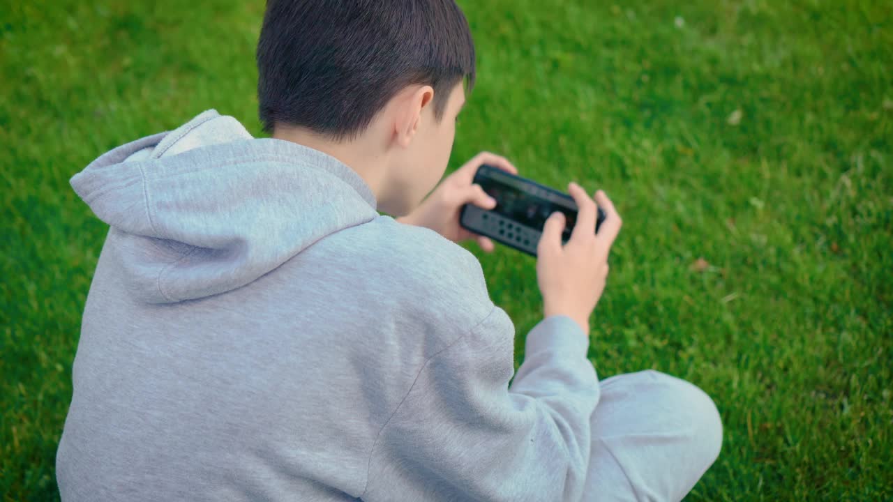 男孩太依赖手机游戏了。孩子不能扔平板电脑和在户外玩视频素材