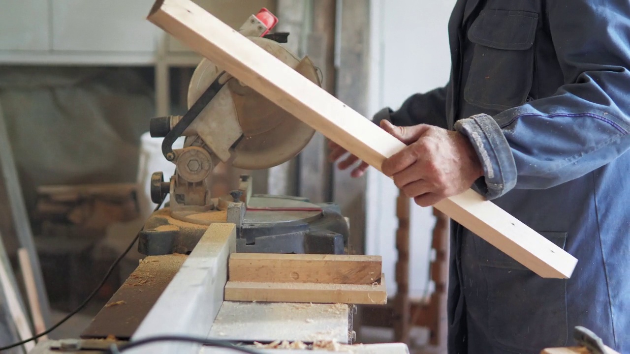 特写:车间里的木匠用圆锯锯木板，在自然光下制作家具部件。木匠和木头一起工作。房屋维修的施工工具。木工工具。视频素材