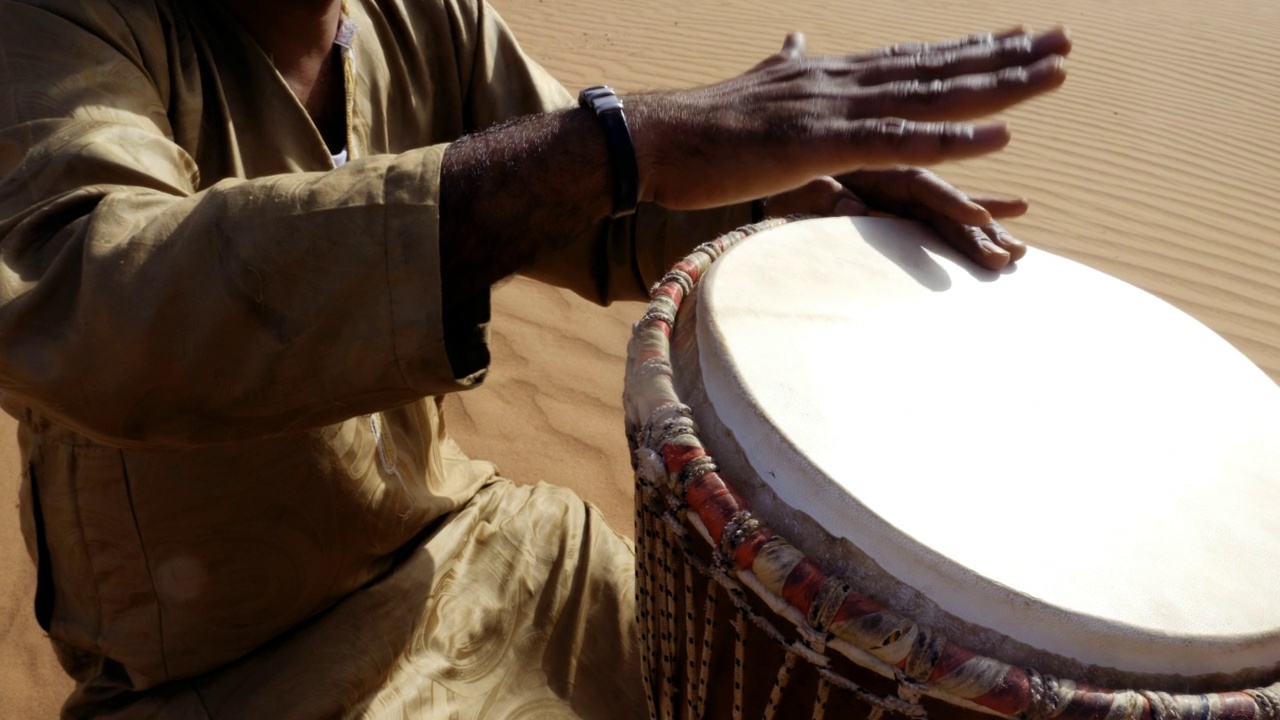 一位摩洛哥男子在沙漠中演奏传统的djembe鼓。视频素材