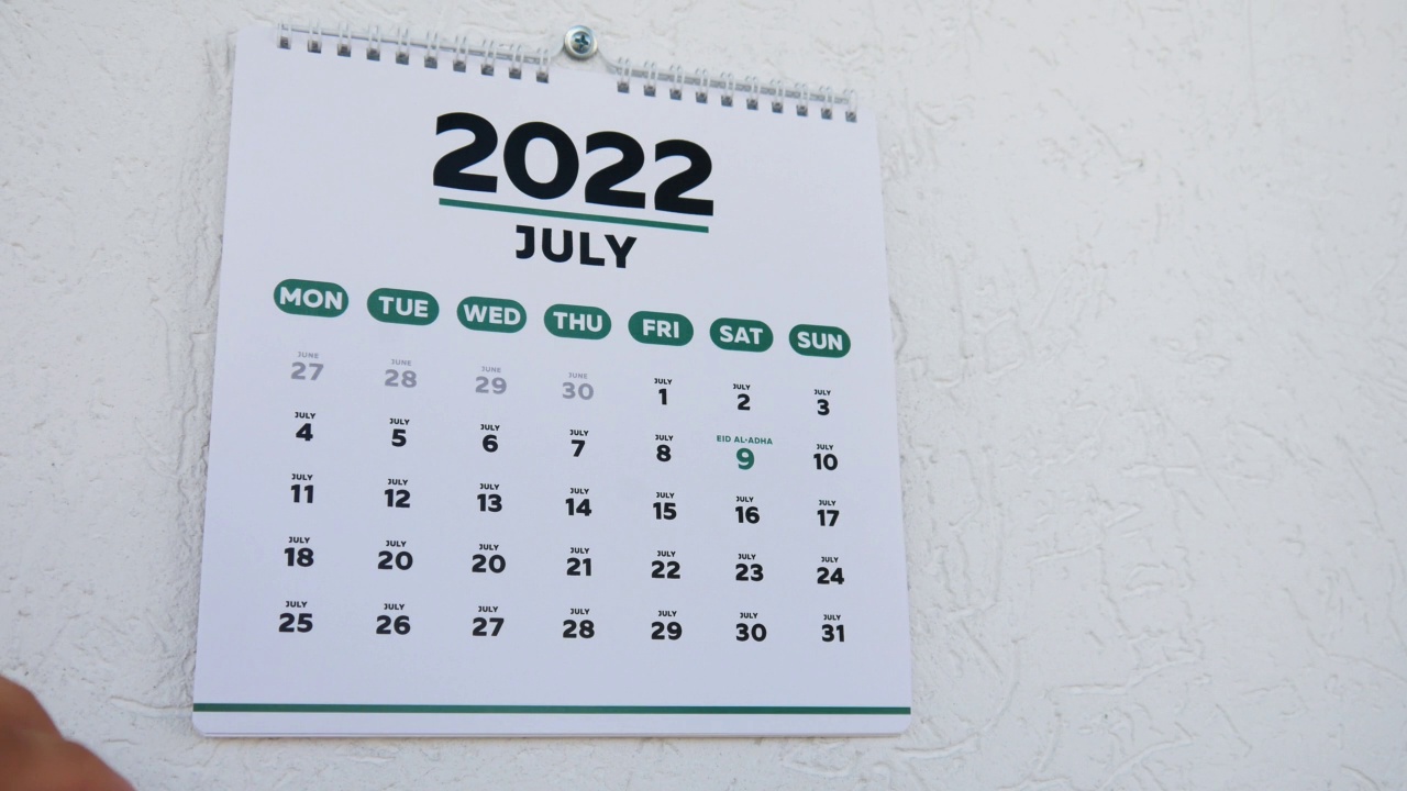 墙上日历的特写，2022年7月，一名男子指着宰牲节日期视频素材
