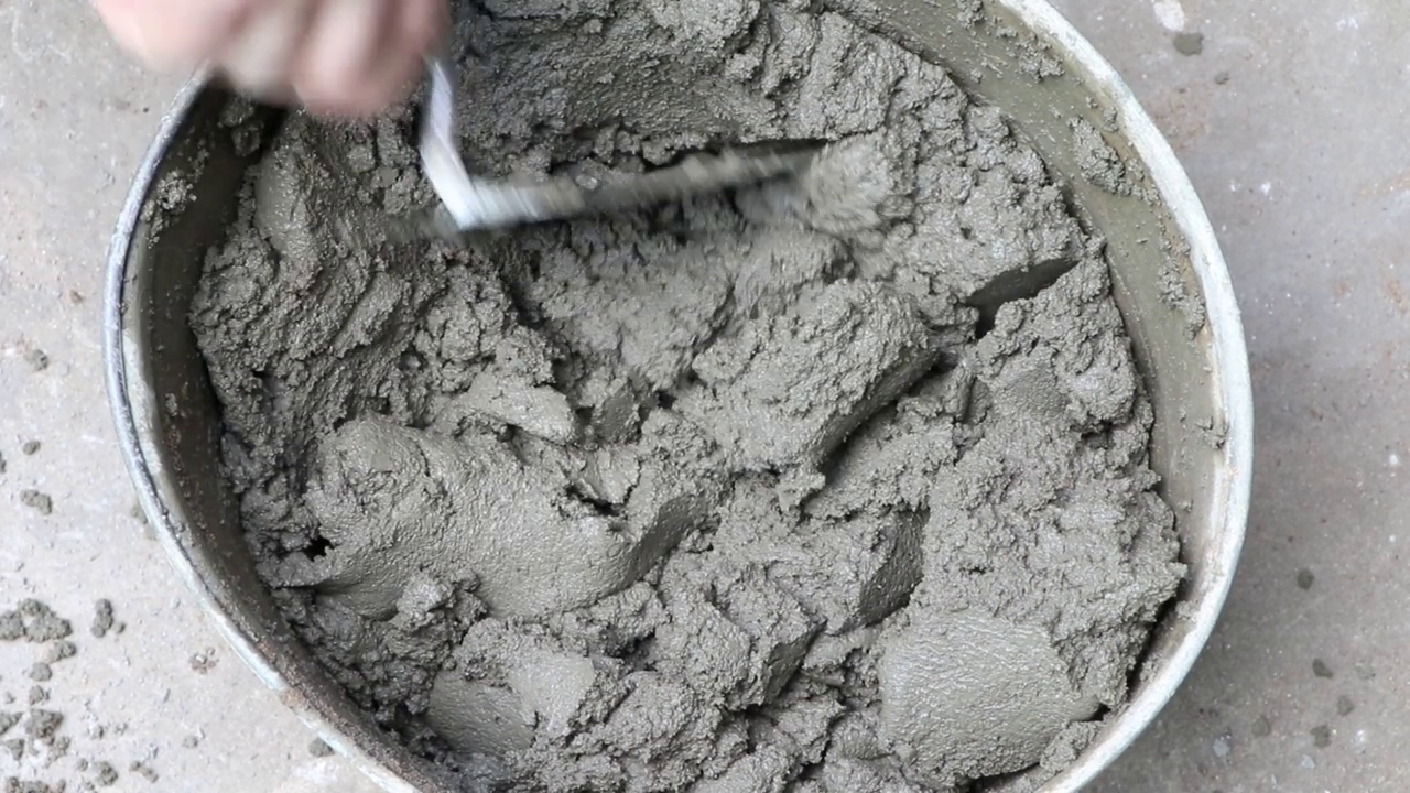 搅拌混凝土砂浆。建筑商使用建筑搅拌机准备水泥砂浆。在桶里抹灰。视频下载