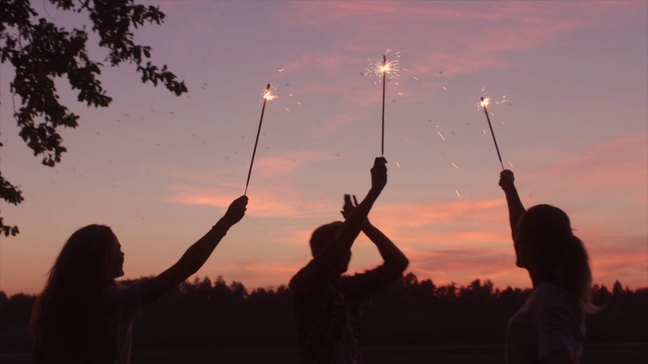 黄昏时分，快乐的年轻人在湖边庆祝，点燃烟火，享受暑假视频下载