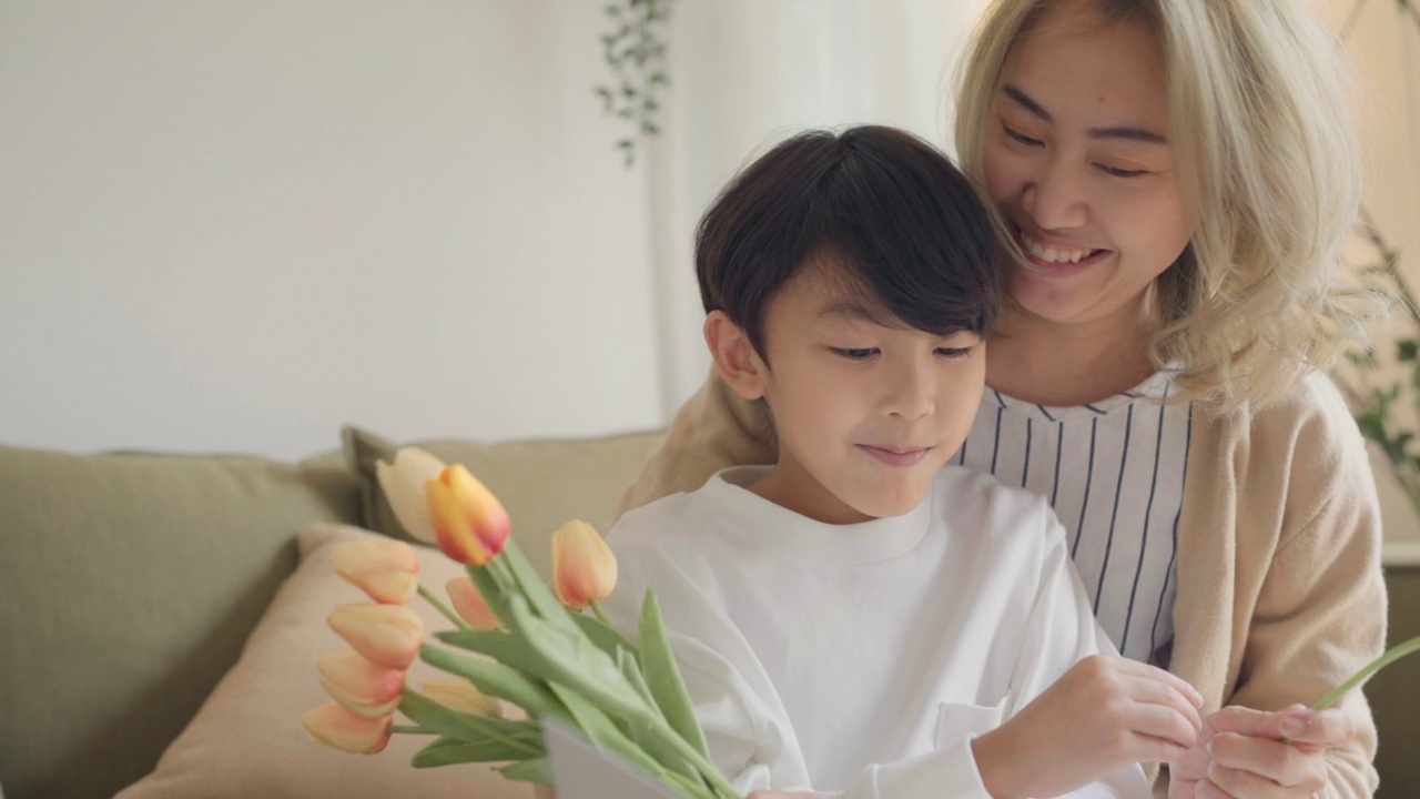 母亲和儿子在家里抱着一束新鲜的郁金香视频素材