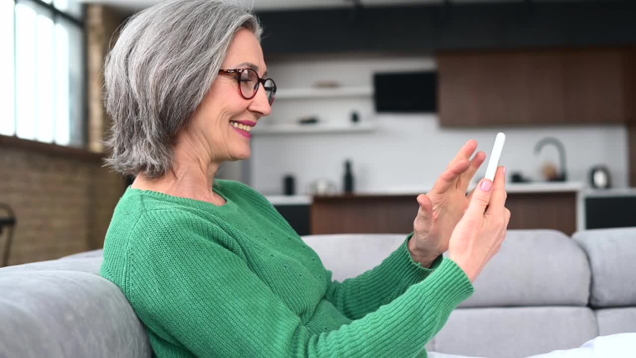 成熟的老年女性在家使用智能手机视频素材