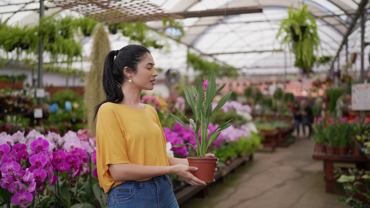一个年轻女人在花园中心买一株植物的画像视频下载