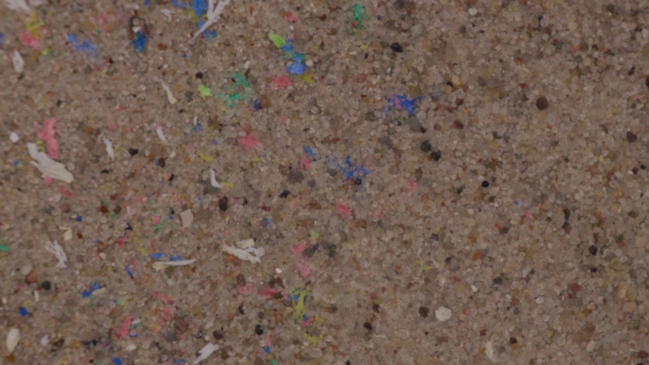 微膏污染环境。塑料微粒在沙地上。视频下载